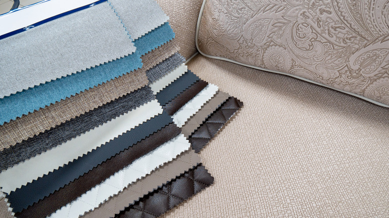 A couch with swatches of different material choices laid across it.