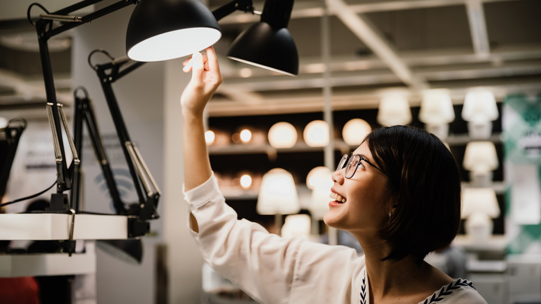 Woman wearing glasses choosing a new lamp to buy at a furnishings store