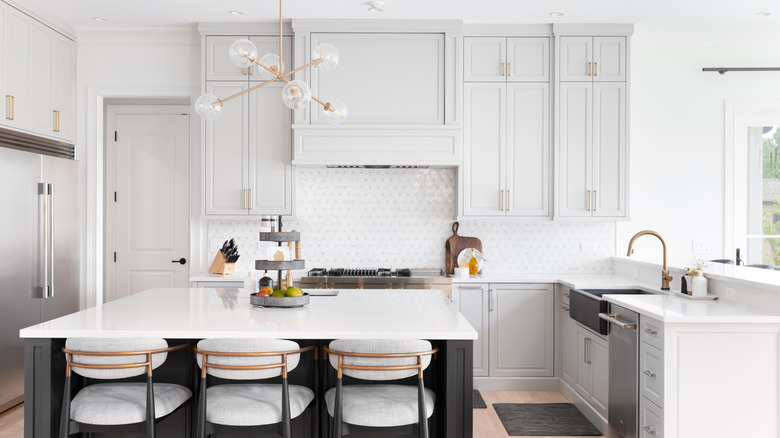 A luxurious kitchen with a large island, gold faucet, and Sputnik chandelier