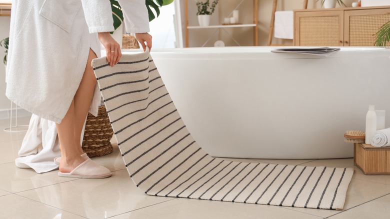 Someone laying down a bathroom mat