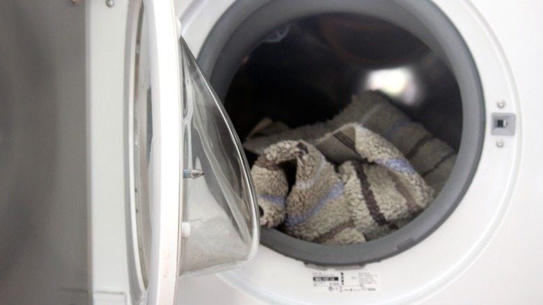 Bath mat sitting in white washing machine with door open