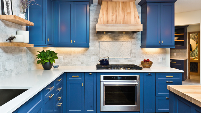 A contemporary kitchen featuring blue cabinets, a center island, hardwood floor and quartz counter.