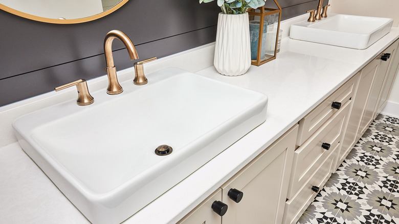 A modern bathroom with a gold sink faucet.