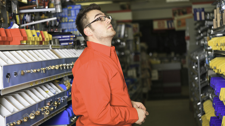 A man looks overwhelmed in the aisle of a hardware store