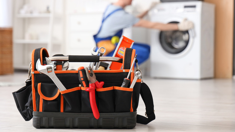 A tool box and a repairman fixing washing machine