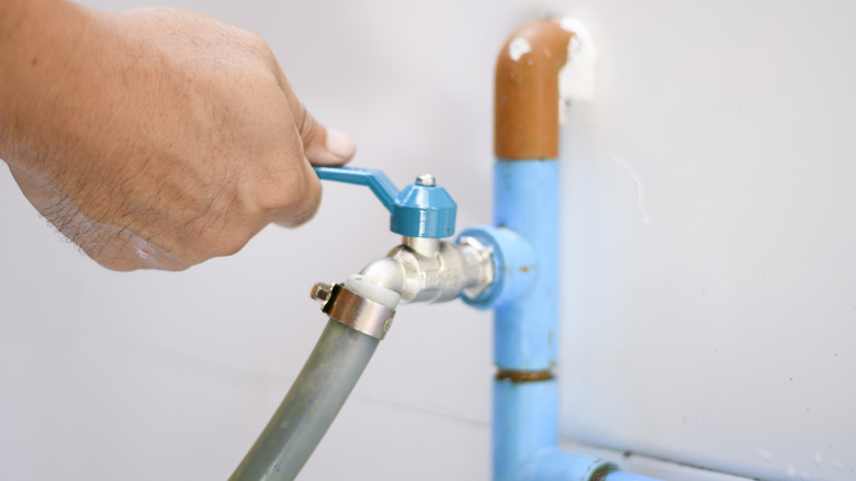 a hand turning a cold water valve off