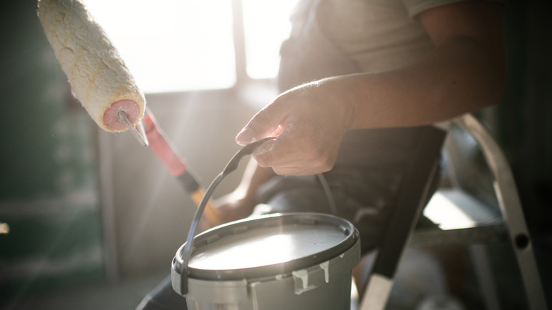 Person holding paint can and paint roller for a home renovation
