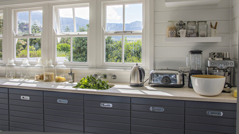 A bright kitchen with a lot of items and appliances on the countertops