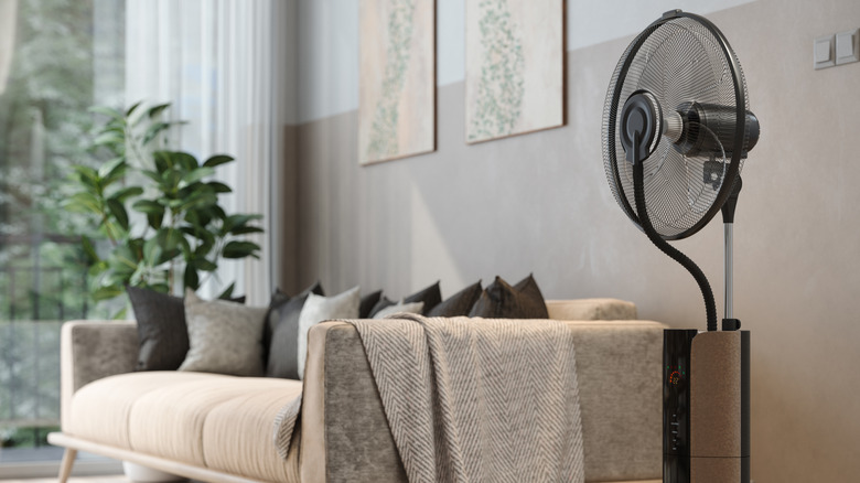 A pedestal fan in the corner of a living room