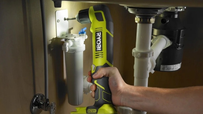 Person using a Ryobi right-angle drill under a sink