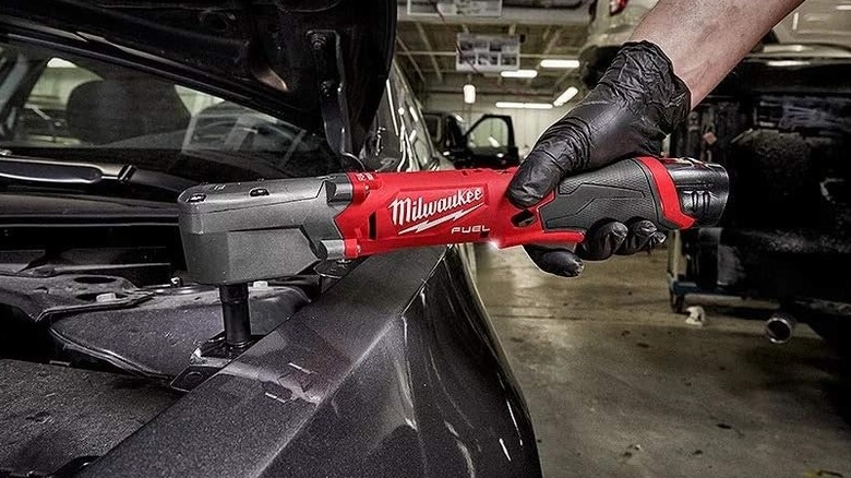Person using a Milwaukee right-angle impact wrench on a car