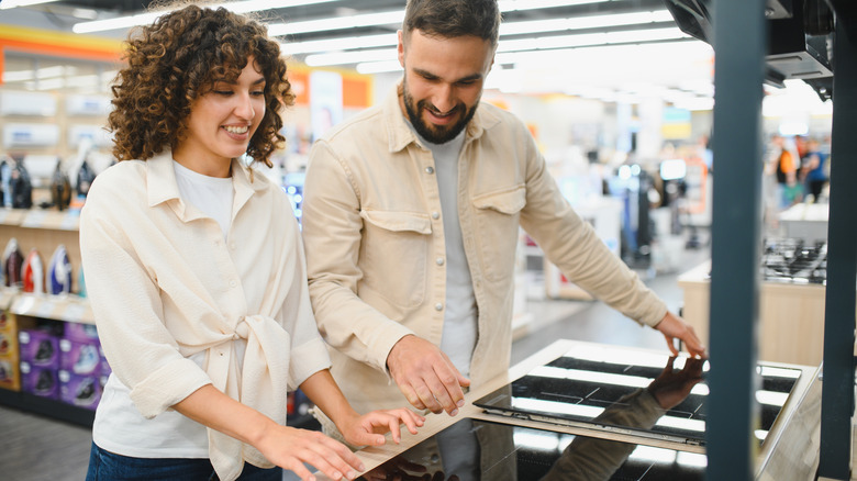 Couple selecting a new induction stovetop in a home appliance store