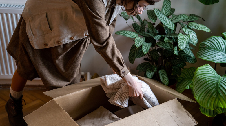 A person putting clothes in a box to donate