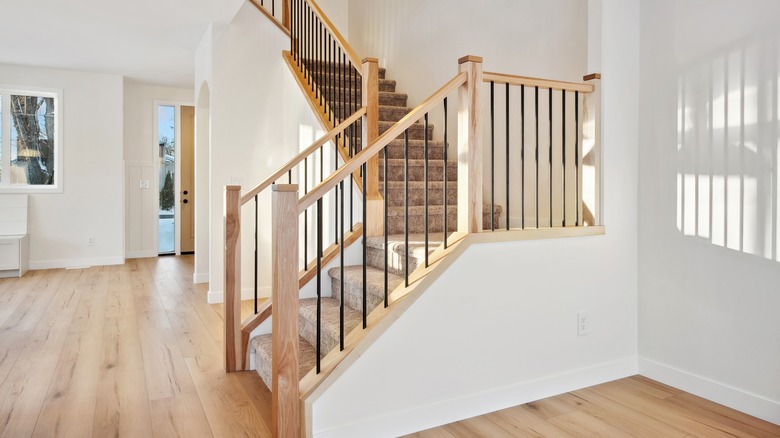 An empty house featuring a prominent staircase with a wooden and metal staircase railing