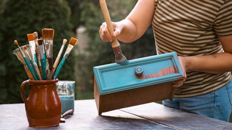 Close up of person painting a drawer blue