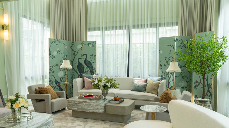 A luxe living room with green curtains, plants, and room dividers
