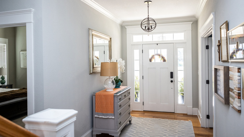 entryway with cabinet, mirror, lamp, flower vase, and wall art