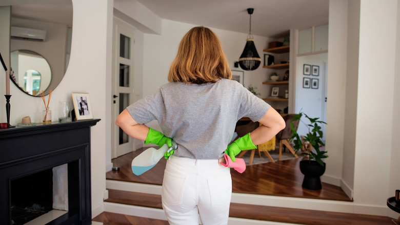 Person holding cleaner and wearing gloves looking around the space