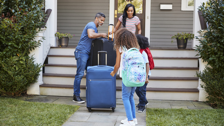 A family standing in front of home with suitcases