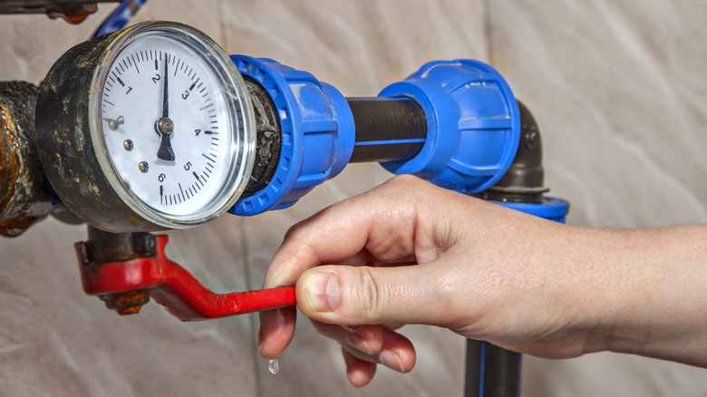 A hand turning a red water valve