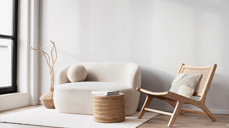 Corner of a room near a large window with a small sofa, chair, coffee table and decor all at almost the same height