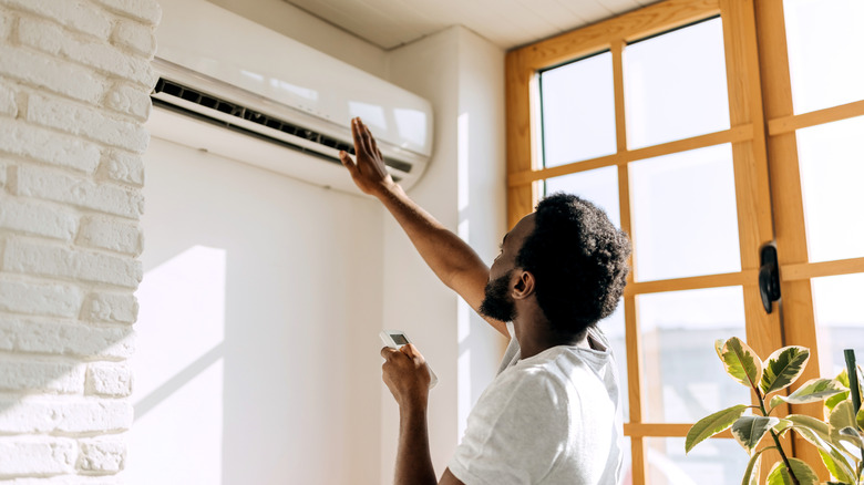 Man turning on an air conditioner using the remote
