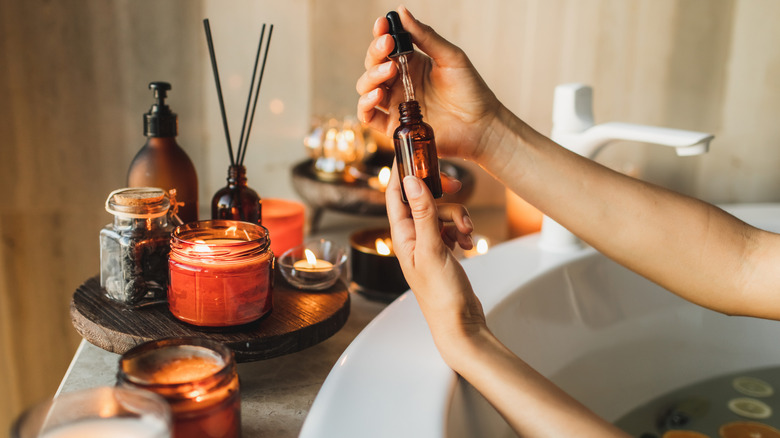 Hands holding essential oil over bath water