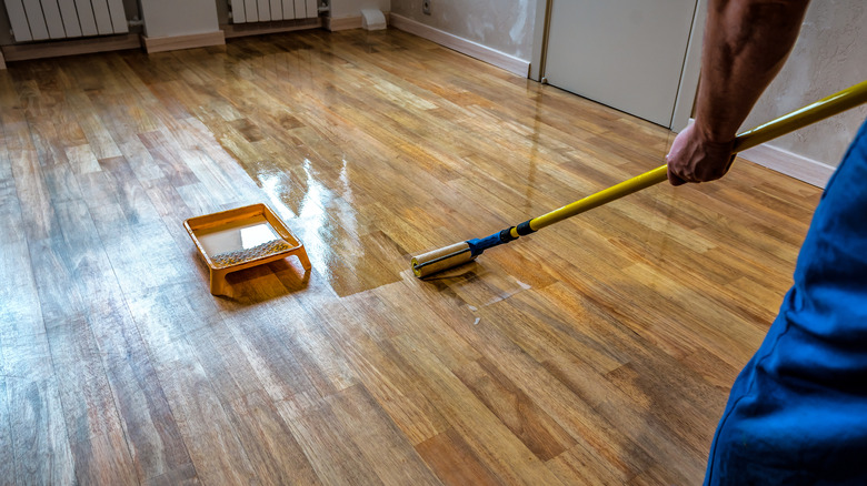 Parquet floor renovation with a person lacquering wood floors