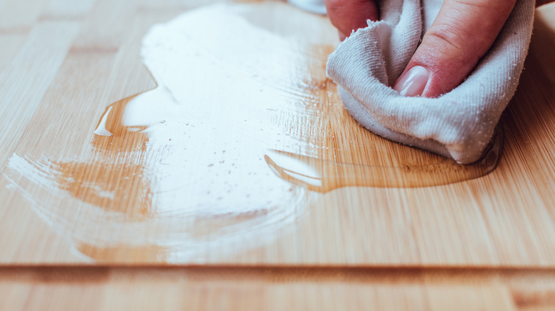 Applying coconut oil on a wooden cutting board