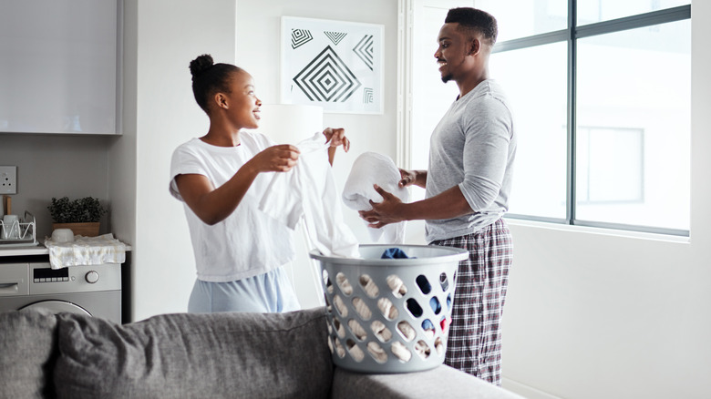 Couple folding laundry from basket