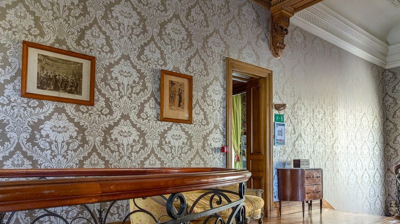 Stair landing in home with grey and white textured wallpaper and framed photos on the wall.