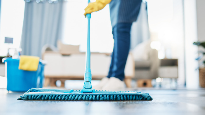 Person using microfiber mop on painted wood floor in home