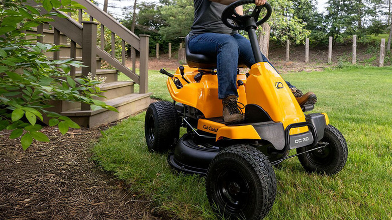 A person using the Cub Cadet CC30 H rear-engine riding lawn mower