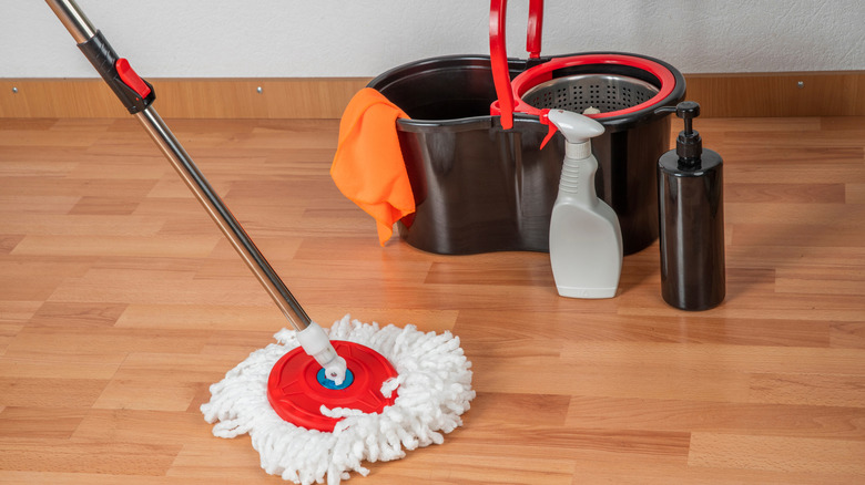 Mop, bucket, and cleaning solution bottles on laminate floor