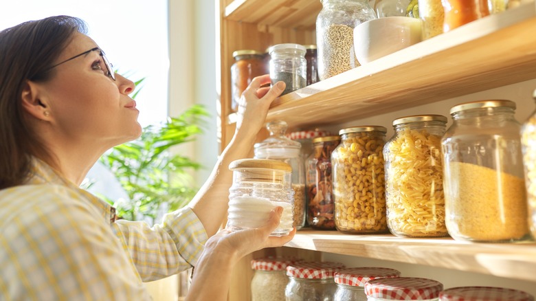 Person pulling jar from open shelf