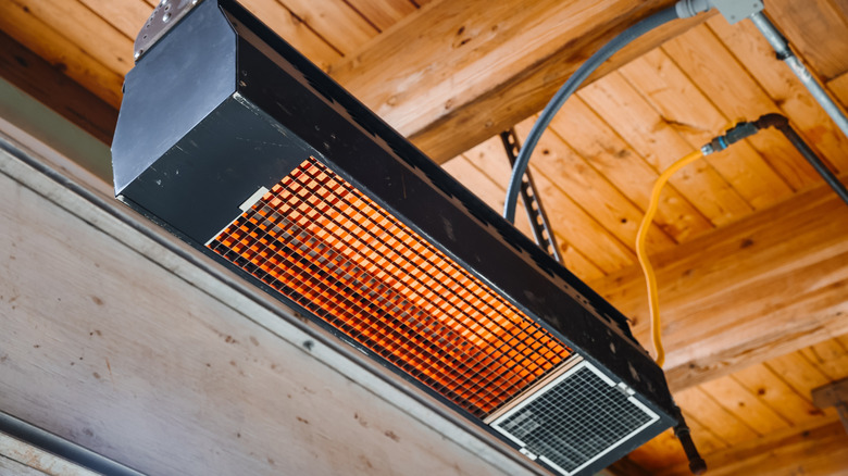 A radiant garage heater mounted to the ceiling and turned on.
