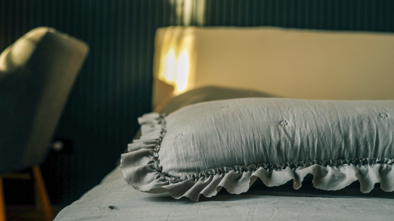 Close-up of a soft pillow with delicate ruffles on a neatly made bed, bathed in gentle morning light