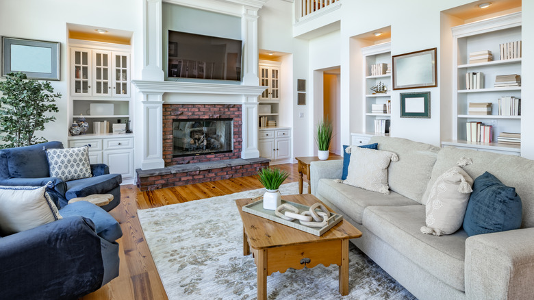 living room with wooden beams, hardwood flooring, sofa, fireplace, and built-in cabinets