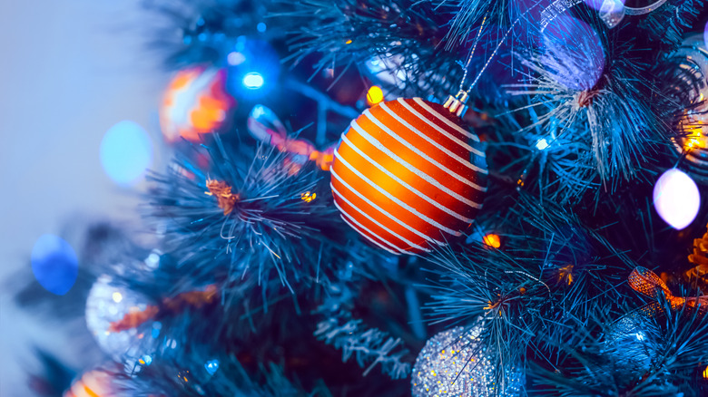 Blue-colored Christmas tree with orange and silver ornaments.