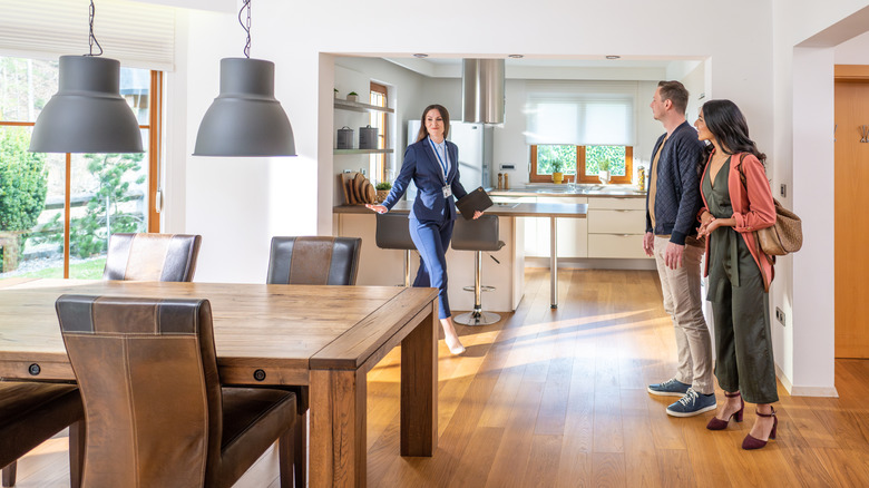 A young couple tours a large kitchen with a real estate agent