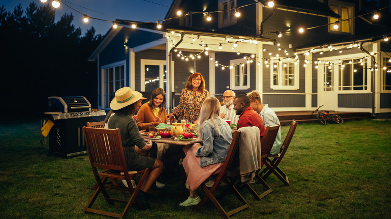 Group of people eating dinner in a backyard
