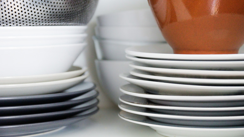 Stacks of plain ceramic plates and bowls in white cabinet