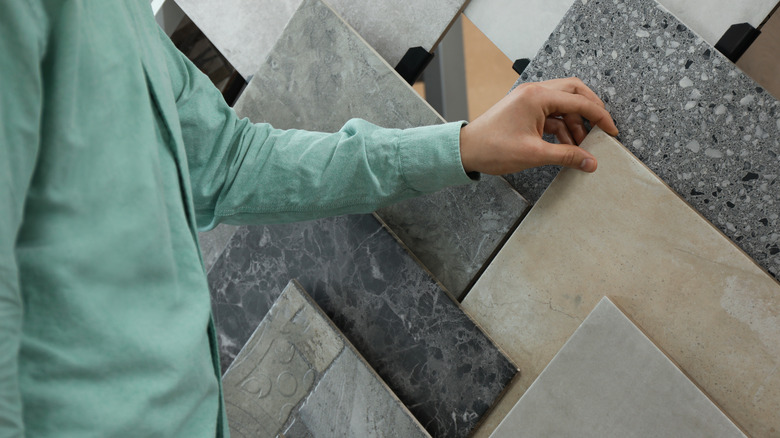 A woman in a light green shirt shopping for kitchen floor tiles.