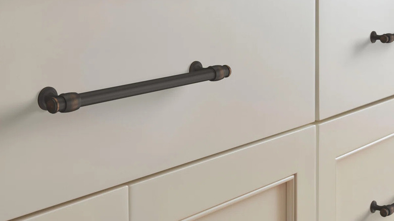 Oil-rubbed bronze door handles on a white kitchen cabinet