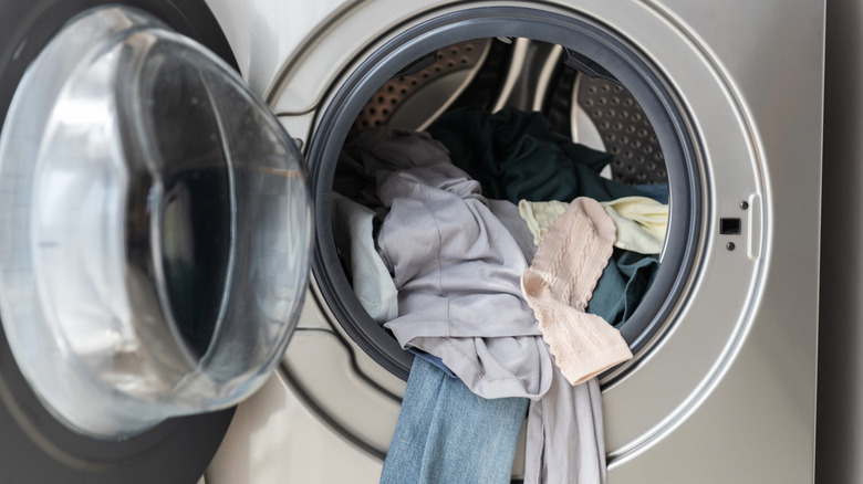 An open front-load washing machine with clothes inside the drum