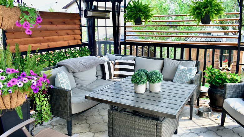 A patio with furniture, plants, and flowers