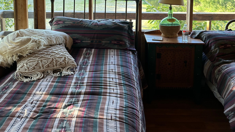 A cabin-style screened sleeping porch with a few beds and other furniture.