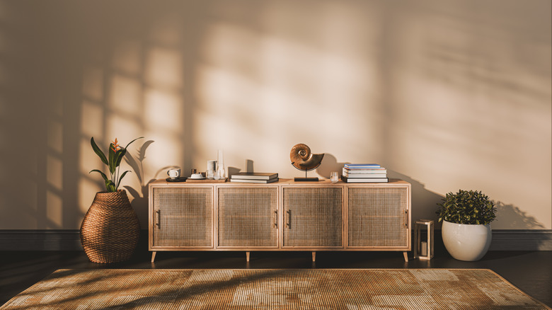 A rattan credenza in someone's living room against a backdrop of brown walls