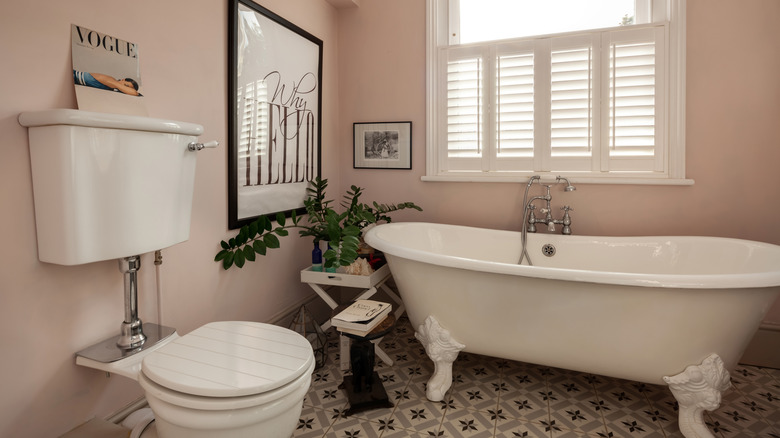 A Victorian-style bathroom painted soft pink features a white high-tank toilet