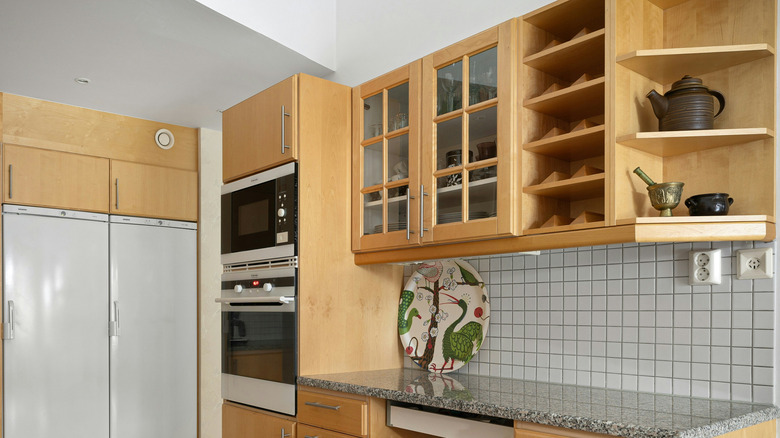 A kitchen with wooden cabinets with a glass front